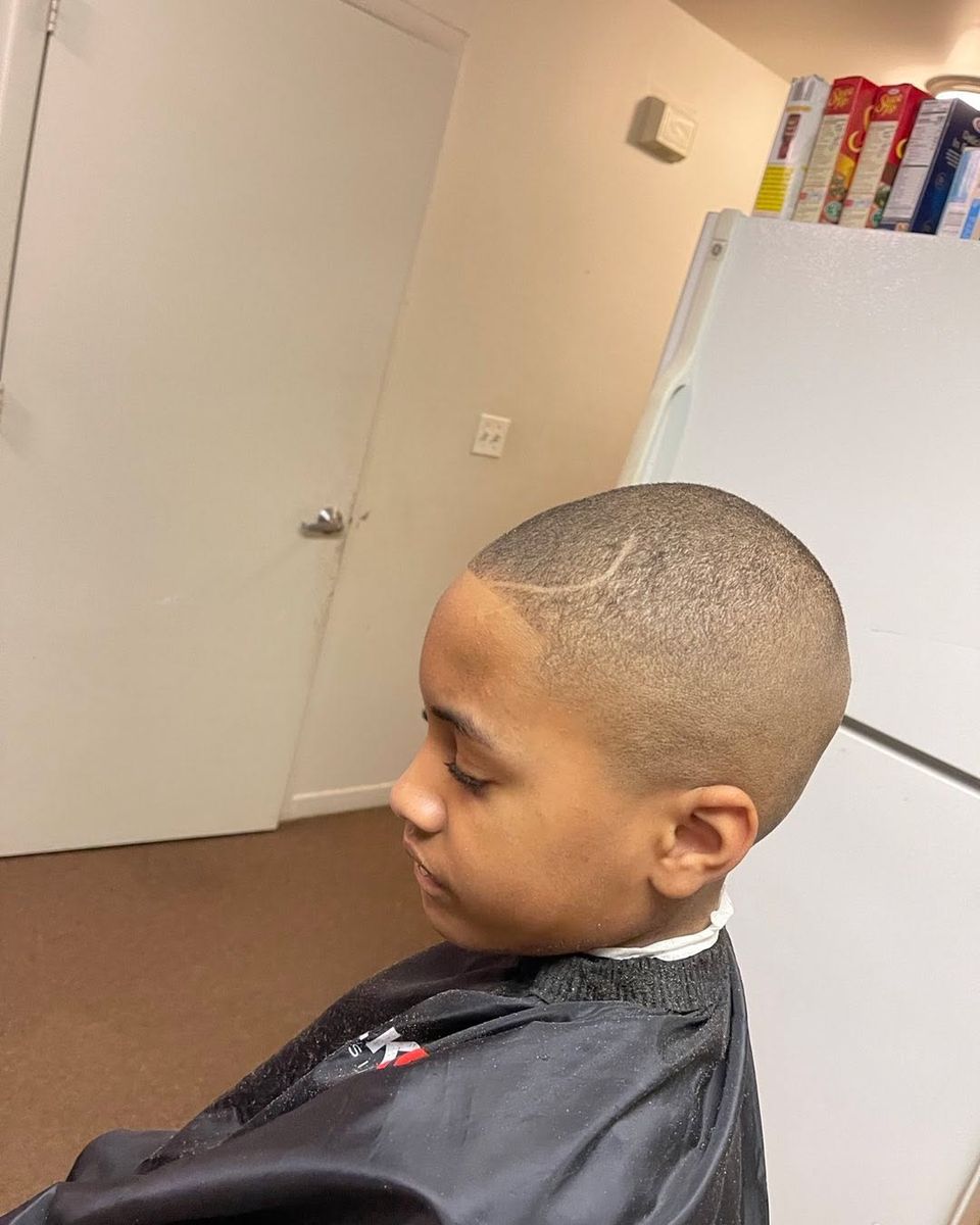 Kids buzz cut with a curved shaved design above the ear and a clean edge-up